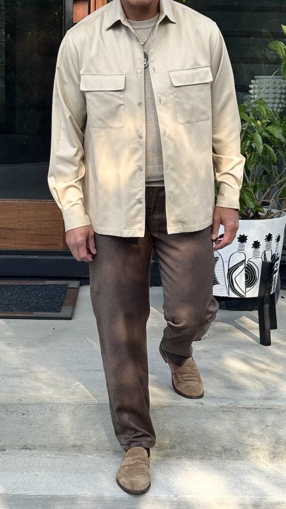 Client in a neutral overshirt, brown trousers and suede loafers