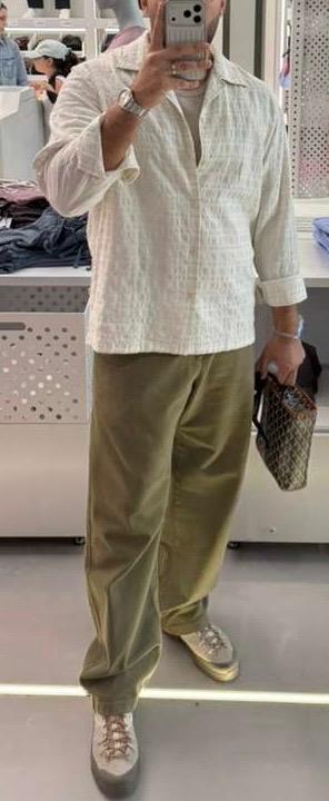 Client in a textured cream overshirt, olive trousers and suede sneakers