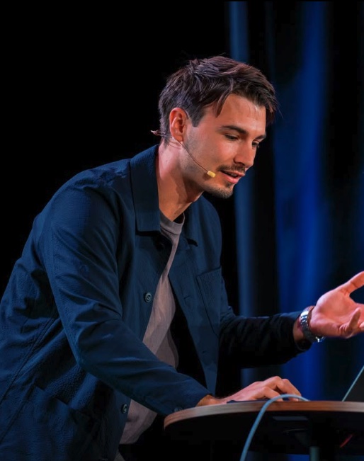 Igor P. speaking on stage in a navy overshirt